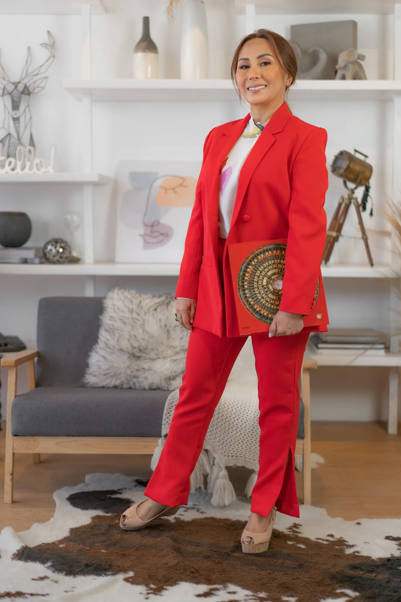Master Judith standing in a red suit with a luopan compass
